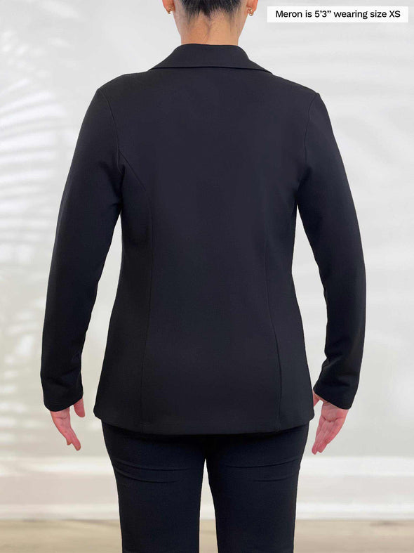 Miik model Meron (5’3”, xsmall) standing with her back towards the camera showing the back of Miik's Adette washable ponte blazer in black 