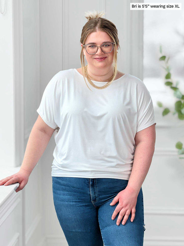 Miik model Bri (5'5", xlarge) smiling wearing Miik's Adisa reversible dolman top in white along with jeans and gold jewelry 