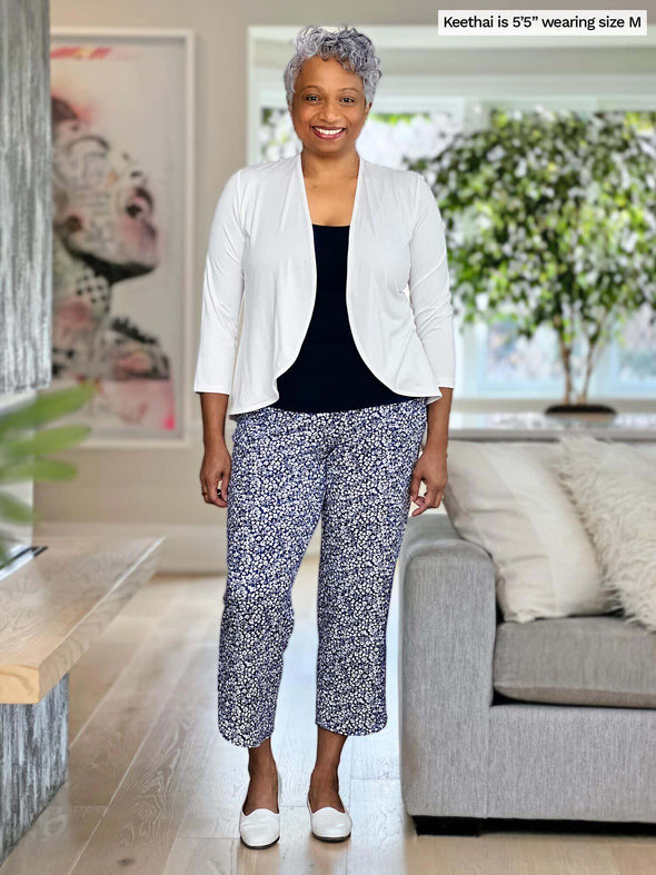Keethai (size medium, 5 foot 5) is wearing the Akira capri pant in baby's breath with a black tank top and white cardigan.