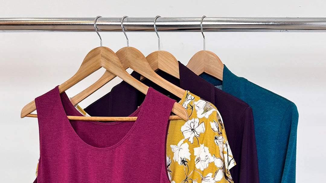 Colourful clothing items on hangers against a white background