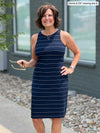 Miik founder Donna (five feet six, small) standing in front of a building smiling wearing Miik's Dani high neck sleeveless dress in navy wide pinstripe 