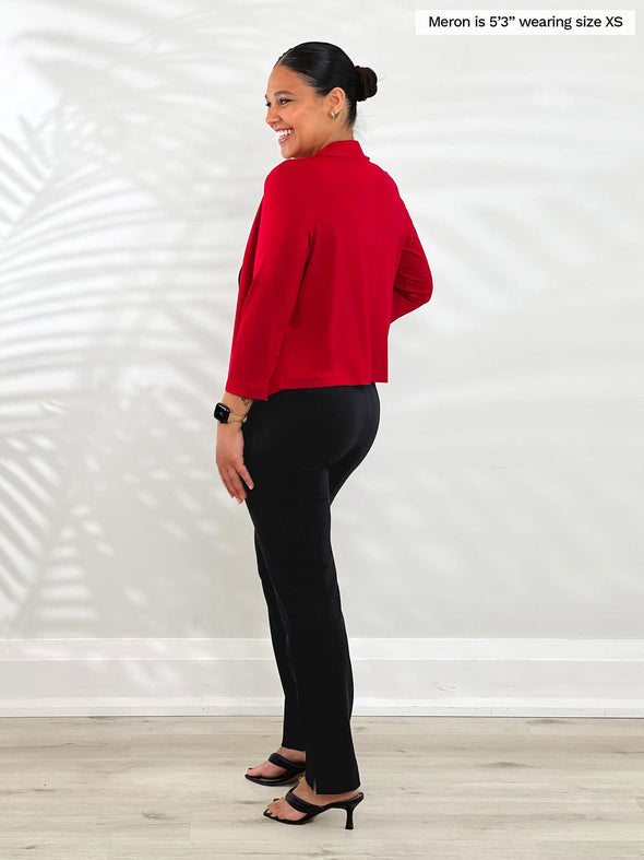 Miik model Meron (5’3”, xsmall) standing with her back towards the camera showing the back of Miik's Dorit boxy soft blazer in poppy red 