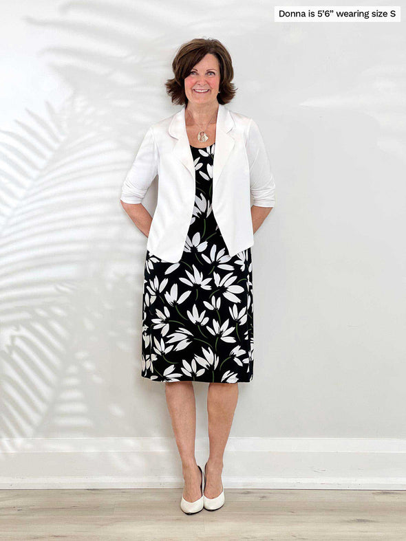 Miik founder Donna (5'6", small) smiling while leaning against to a wall wearing a printed dress with Miik's Dorit boxy soft blazer in white 