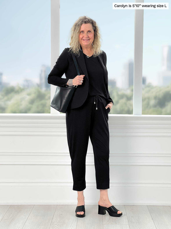 Miik model Carolyn (5'10", large) smiling wearing Miik's Emily soft blazer in black along with a capri jumpsuit in the same colour 