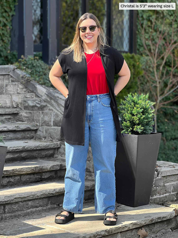 Miik model Christal (5'3", large) smiling wearing Miik's Evie short sleeve pocket cardigan in black along with a poppy red tee and jeans