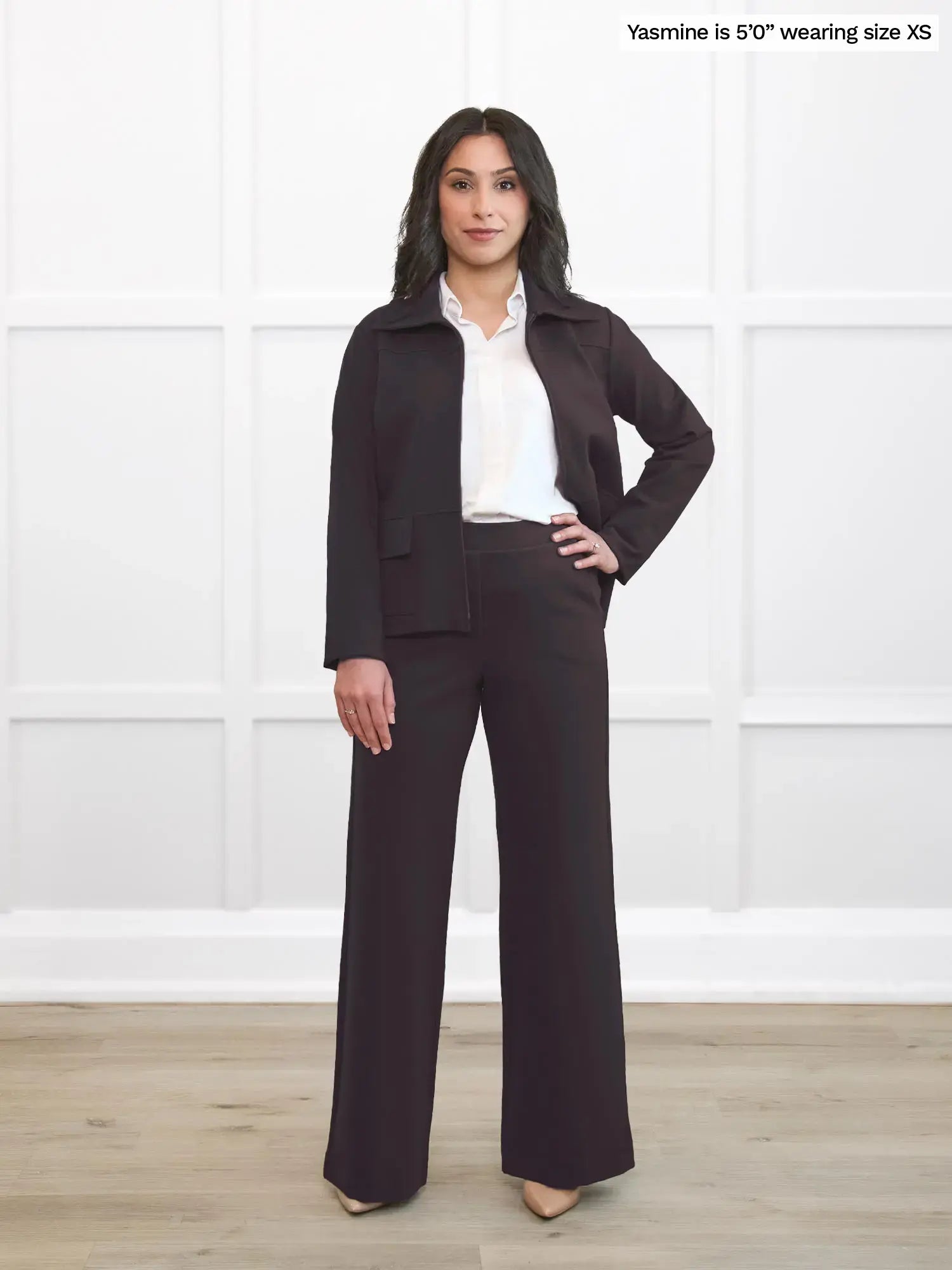 Woman wearing a dark brown suit with a white shirt against a white background