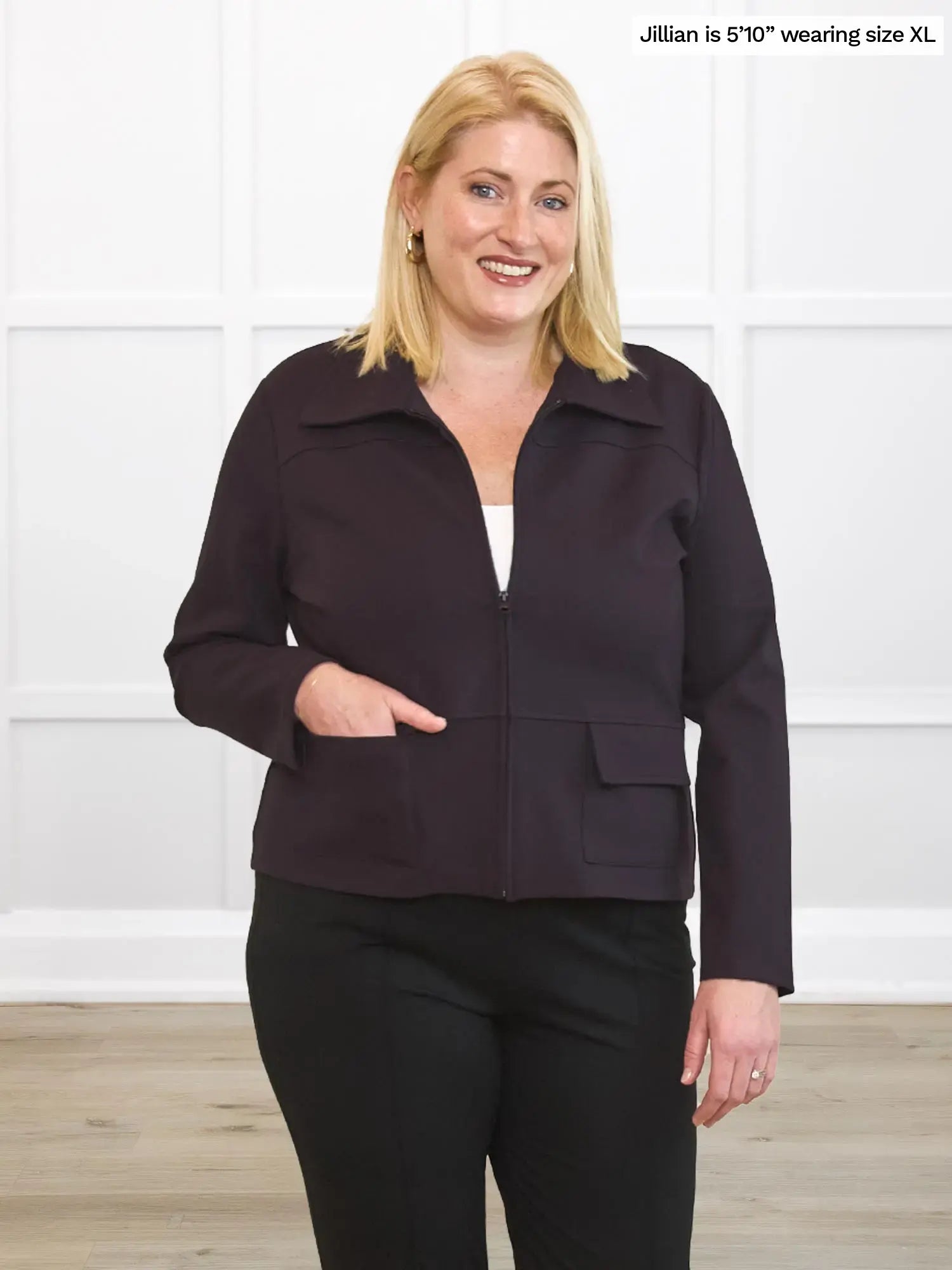 Woman wearing a dark brown jacket and black pants against a white background