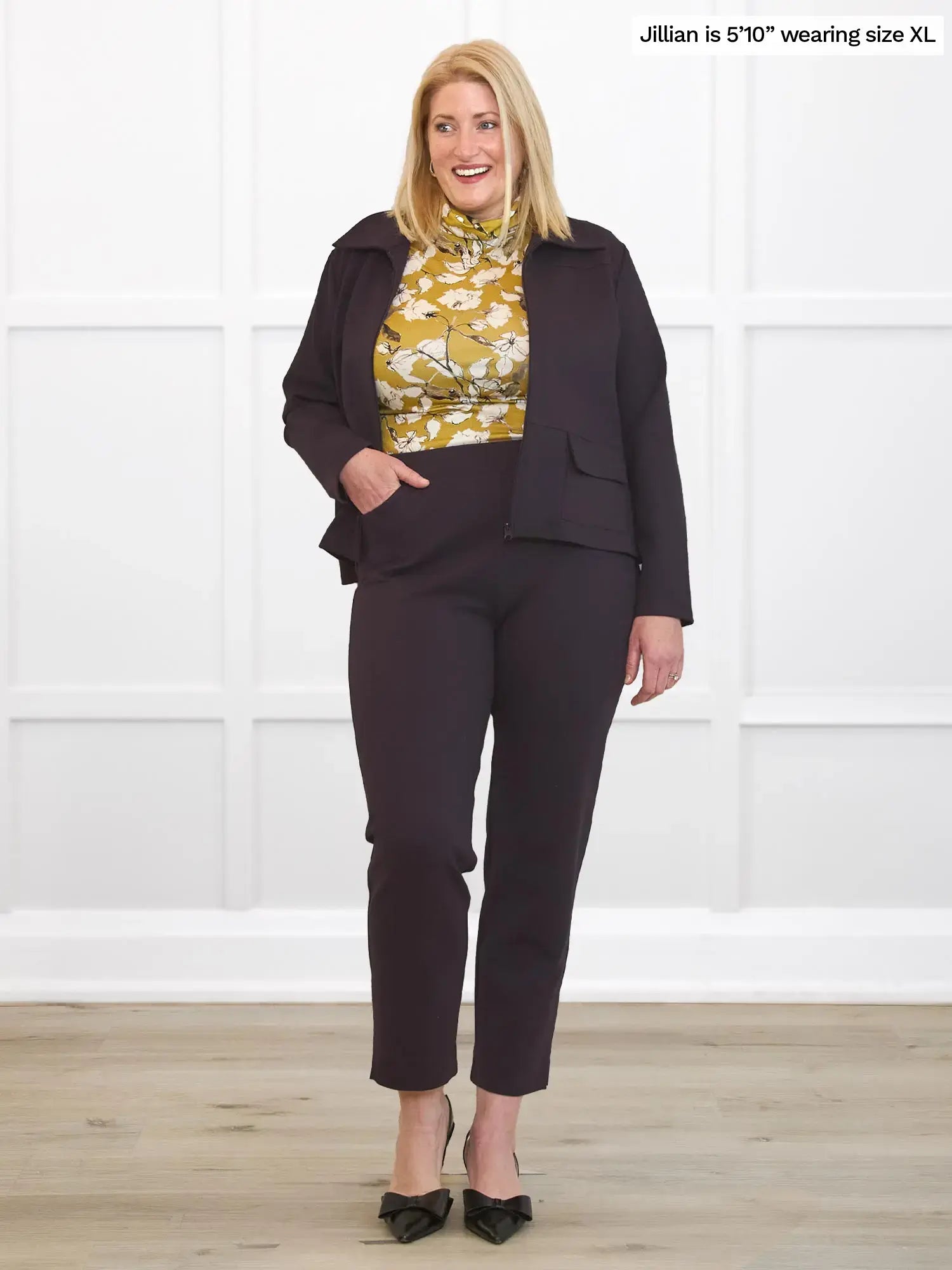 Woman wearing a dark brown outfit with a floral top against a white background