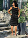 Miik model Meron (5’3”, xsmall) standing with her back towards the camera showing the back of Miik's Jaaron reversible knee length tank dress