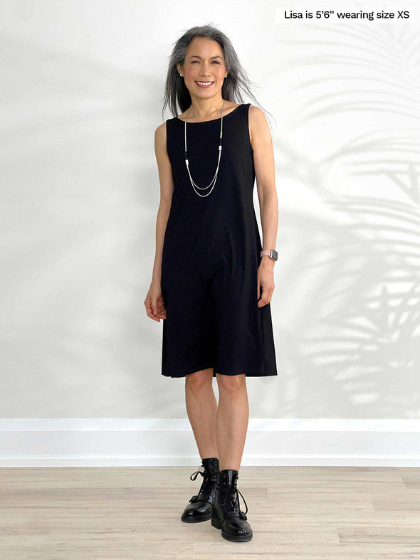 Miik model Lisa (5'6", xsmall) smiling wearing Miik's Jaaron reversible tank dress in black and boots in the same colour 