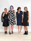 Miik models Bonnie, Kaitlin, Lisa and founder Donna all standing next to each other wearing the same dress: Miik's Jaaron reversible tank dress. They are all styling the dress in different ways. Bonnie is wearing in black, Kaitlin in white lily, Donna in navy and Lisa in black wide pinstripe 
