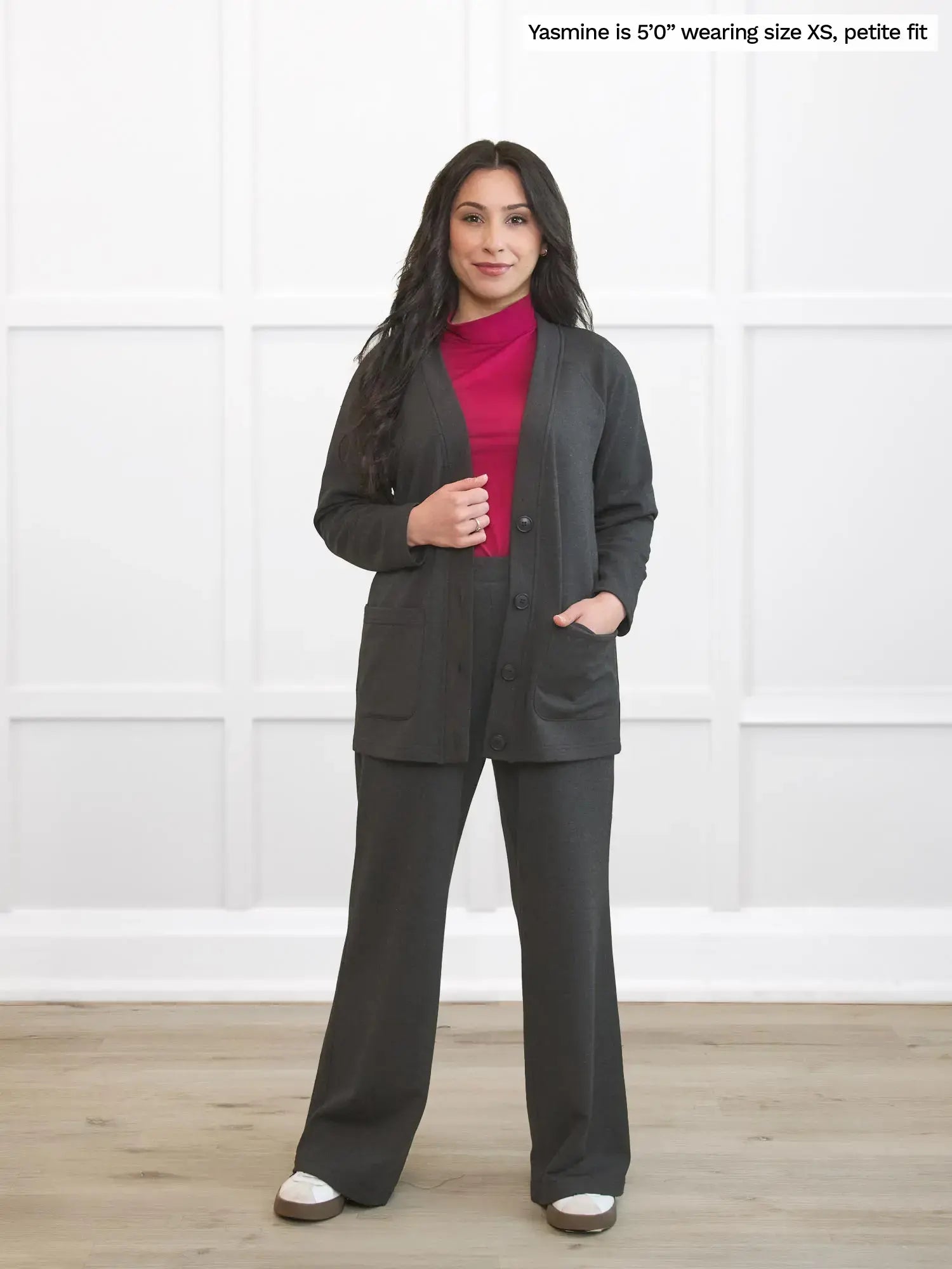 Woman wearing a gray suit with a pink shirt against a white background