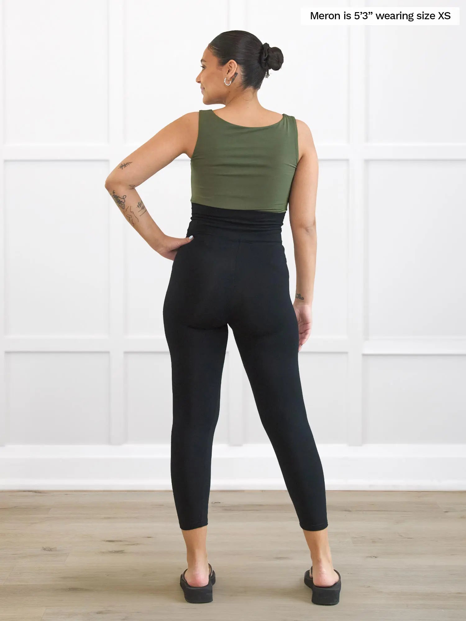 Miik model Meron (5’3”, xsmall) standing with her back towards the camera showing the back of Lisa2 high waisted capri legging in black