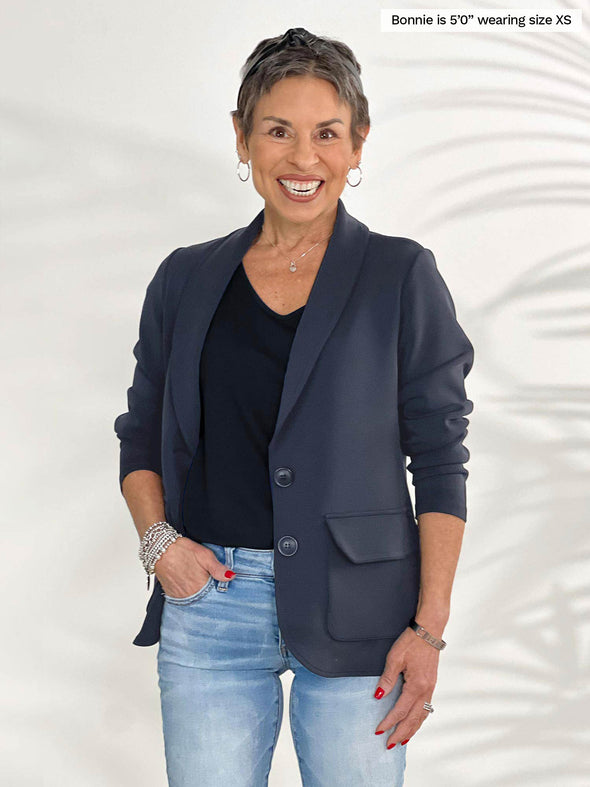 Miik model Bonnie (5'0", xsmall, petite) smiling wearing Miik's Maeva LightLuxe washable blazer in graphite with a black tee and jeans 