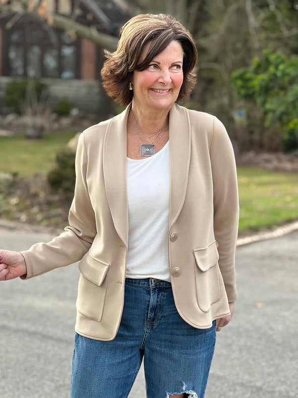 Miik founder Donna (5'6", small) smiling and looking away wearing Miik's Maeve LightLuxe washable blazer in wheat along with a natural tank top and jeans 