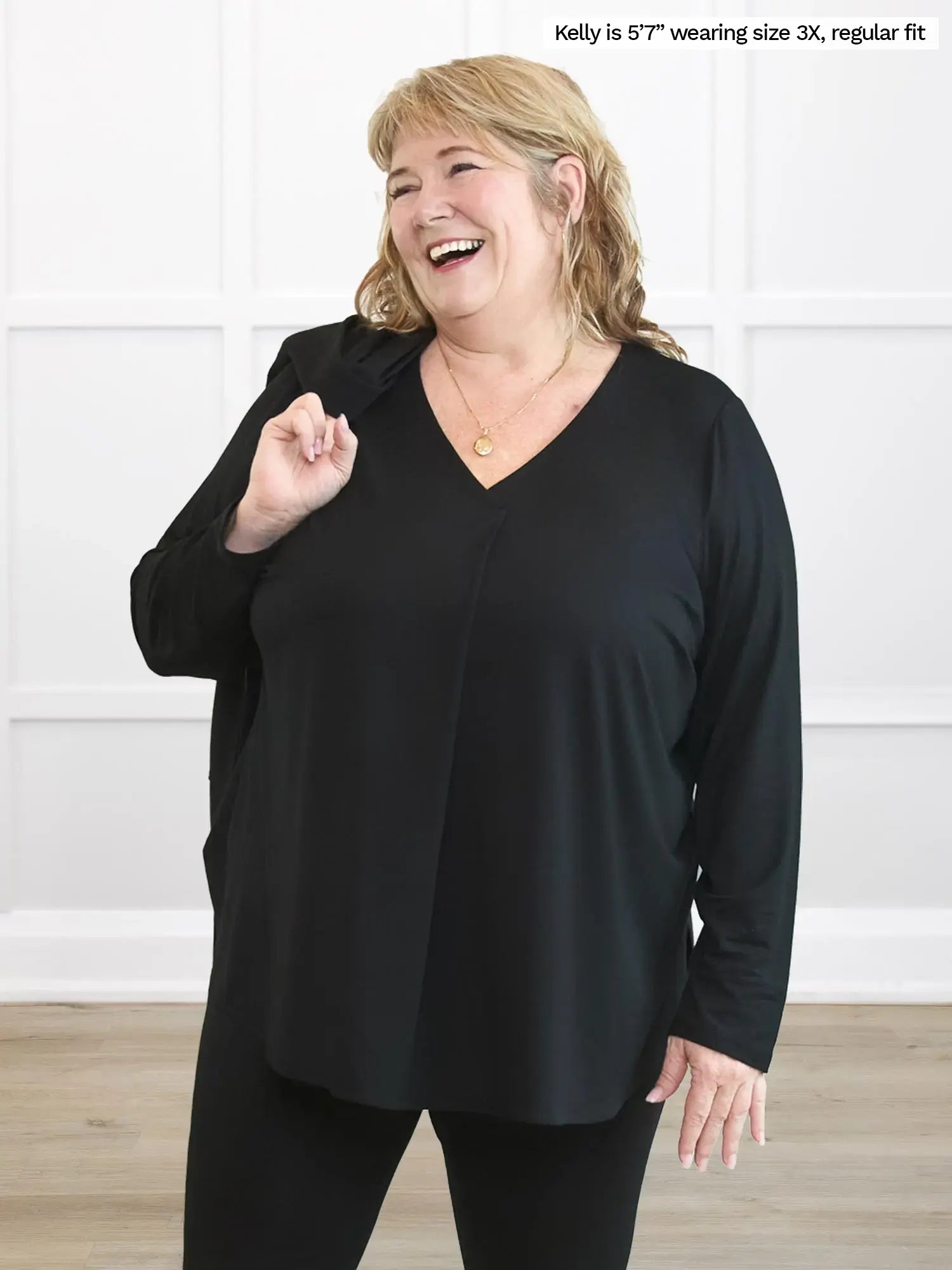 Woman wearing a black long-sleeve top in a white room