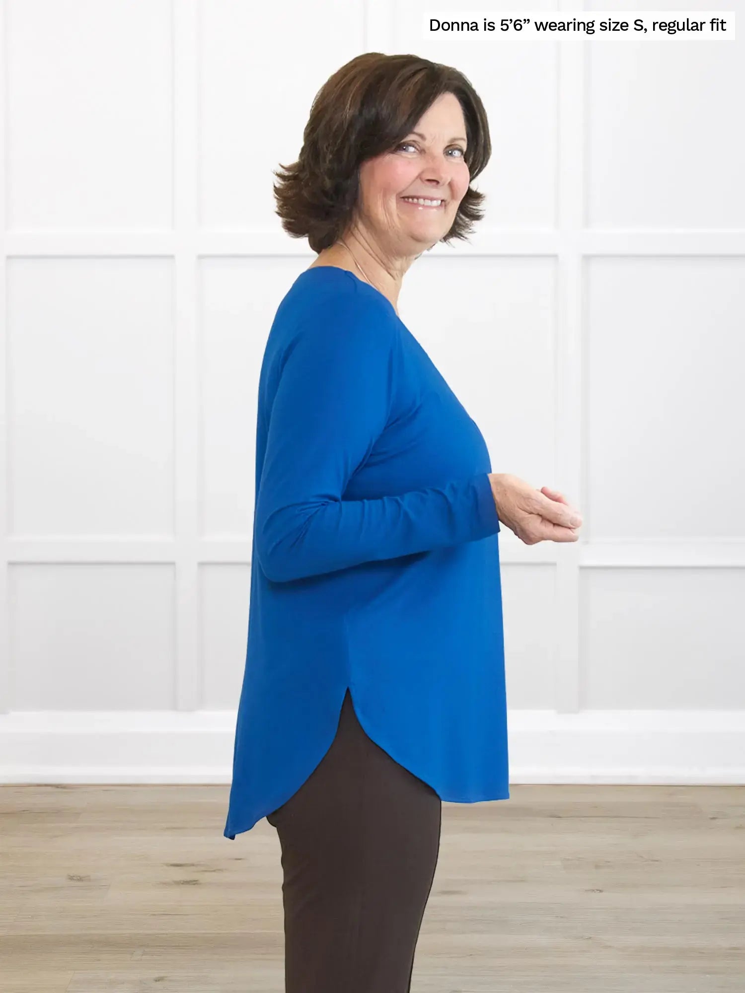 Woman wearing a blue top and dark pants against a white background