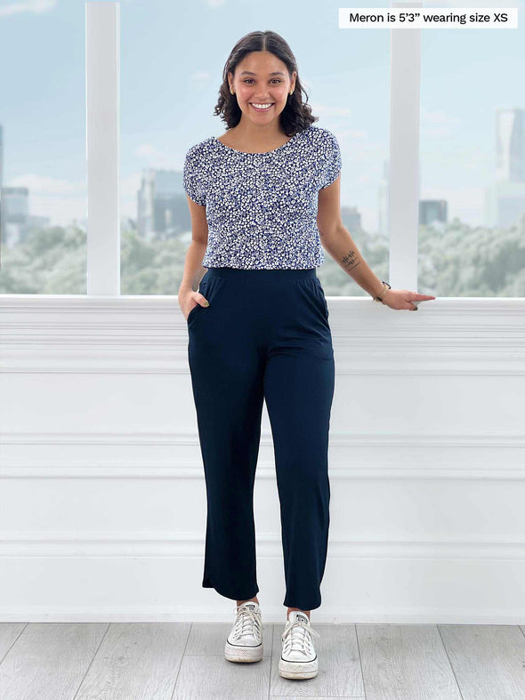 Woman standing in front of a window wearing Miik's Rio reversible dolman tee in blue ditsy print and pants