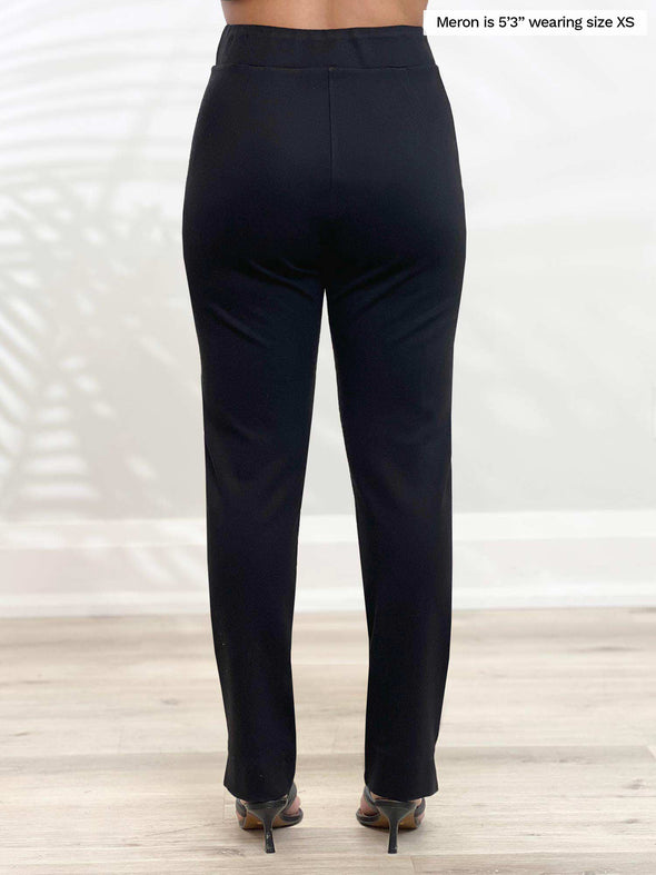 Miik model Meron (5’3”, xsmall) standing with her back towards the camera showing the back of Miik's Roma pull-on straight leg ankle pant in black