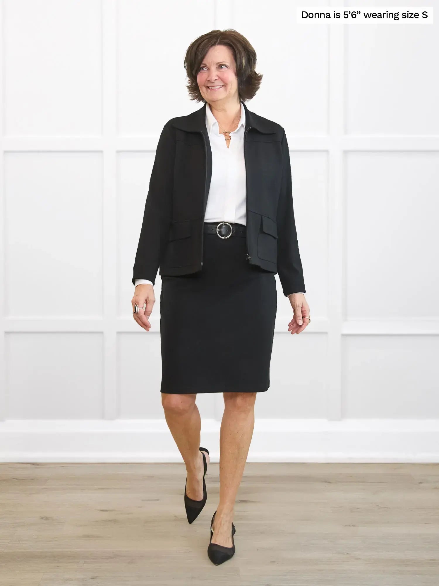 Woman wearing a black suit with a white shirt against a white background