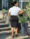 Miik model Meron (5’3”, xsmall) standing with her back towards the camera showing the back of Miik's Salma striped pencil skirt