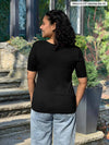 Miik model Meron (5’3”, xsmall) standing with her back towards the camera showing the back of Miik's Shani reversible half sleeve square neck top