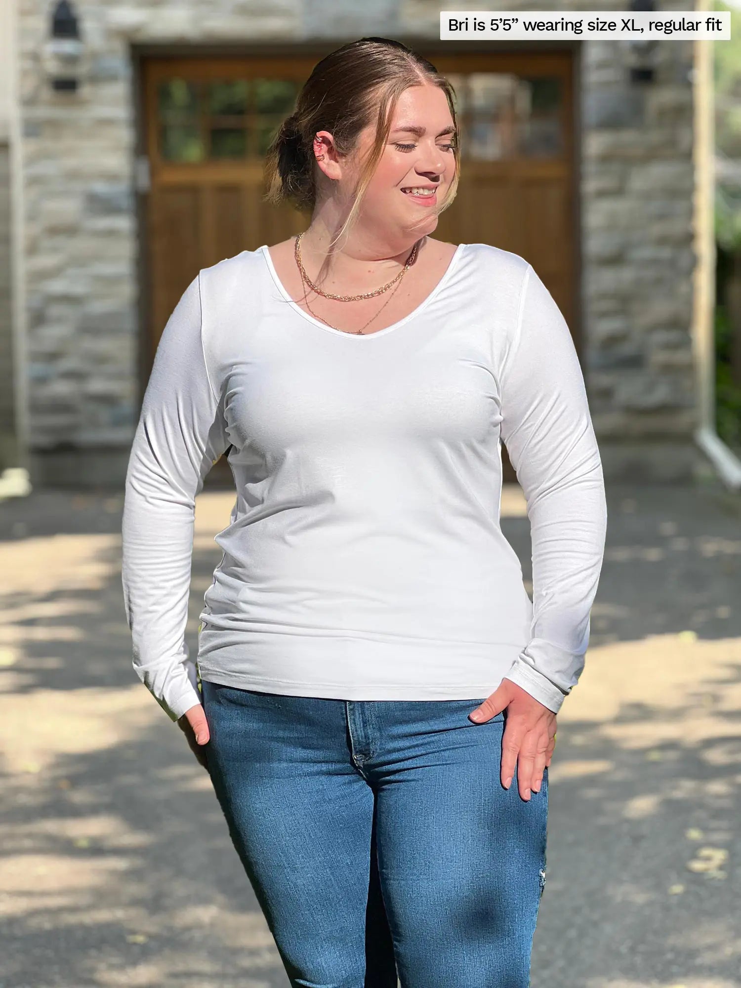 Miik model Bri (size XL) is wearing the Shannon long sleeve reversible t-shirt in white with blue jeans.