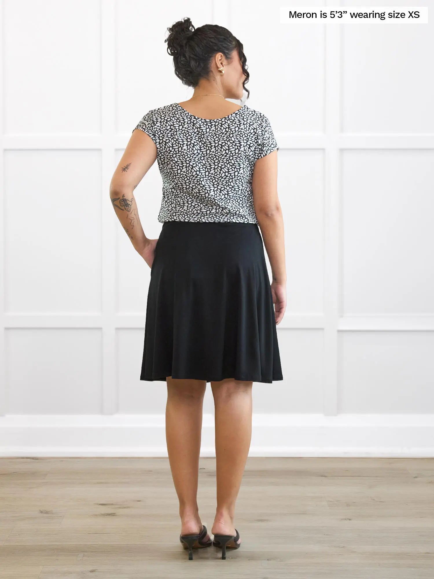 Miik model Meron (5’3”, xsmall) standing with her back towards the camera showing the back of Shima flowy pocket skirt in black