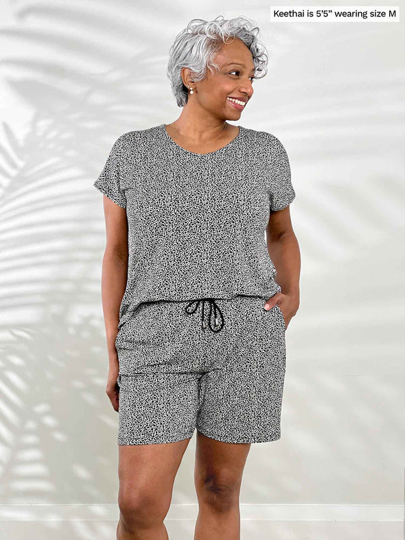 Miik model Keethai (5'5", medium) smiling while looking away wearing Miik's Tanya short sleeve open-back romper in pebble print
