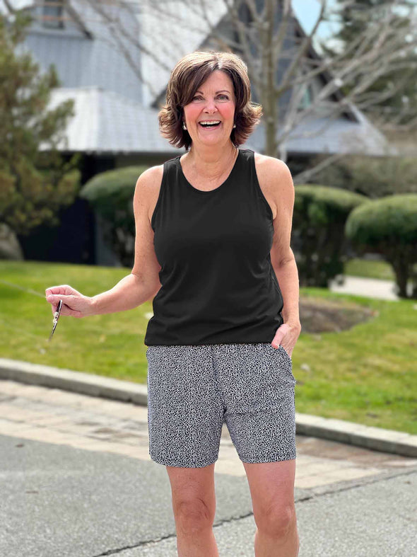 Miik founder Donna (5'6", small) smiling wearing a printed short in pebble along with Miik's Teanna scoop neck tank top in black