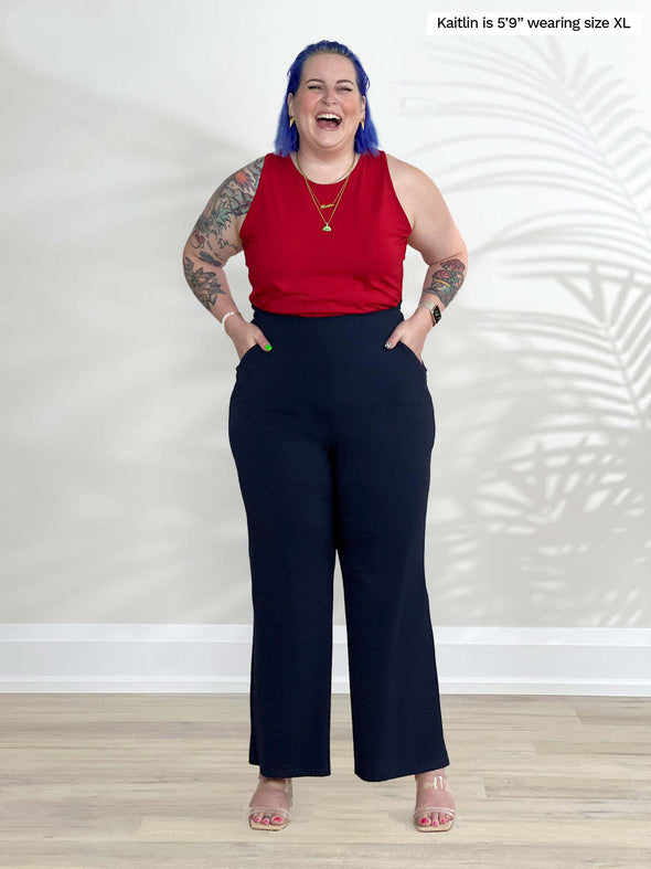 Miik model Kaitlin (5'9", xlarge) laughing wearing Miik's Teanna scoop neck tank top in poppy red with a navy pant