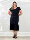 Miik model Christal (5'3", medium) smiling wearing Miik's Zilma reversible puff sleeve midi dress in black