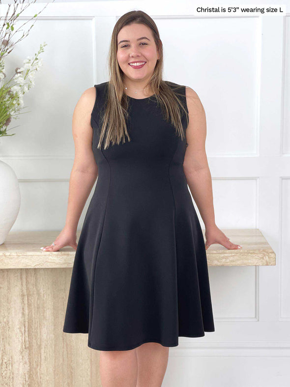 Miik model Christal (five feet three, size large) smiling wearing Miik's Valerie sleeveless fit and flare dress in graphite