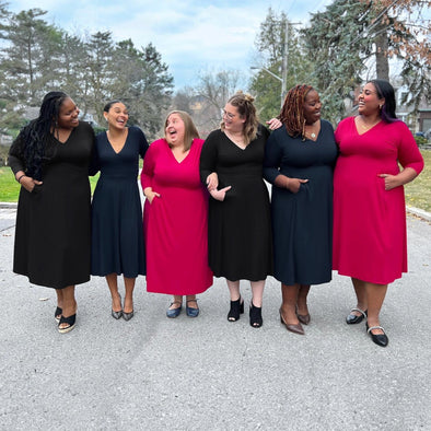 6 Miik women of different sizes standing and laughing next to each other.
