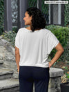 Miik model Meron (5’3”, xsmall) standing with her back towards the camera showing the back of Miik's Adisa reversible dolman top in white 
