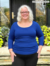 Miik model Colleen (5'3", xlarge) wearing Miik's Akari side ruched reversible top in blueberry and black leggings