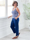 Miik founder Donna (5'6", small) smiling while standing in front of a window/white wall wearing Miik's Akira tulip hem capri pant in ink blue along with a printed tank top and sandals 