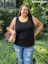 Miik model Sarita (5'7", size 2X, plus size) smiling wearing a ripped jeans with Miik's Alanis relaxed tank top in black