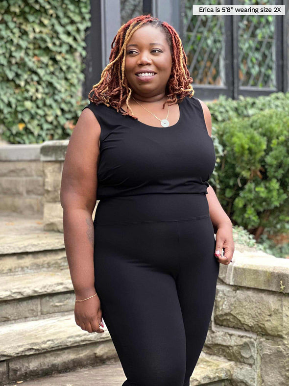Miik model Erica (5'8", size 2x, plus size) smiling and looking away while wearing Miik's Alanis relaxed tank top in black and a legging in the same colour 