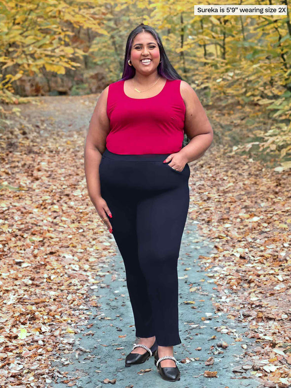 Miik model Sureka (5'9", size 2x, plus size) smiling wearing Miik's Alanis relaxed tank top in bordeaux tucked in a dress pant in black