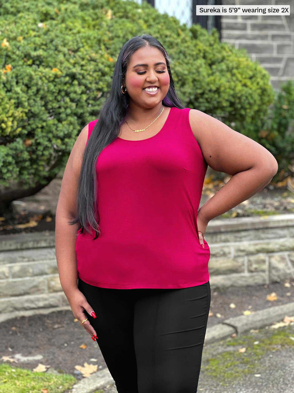 Miik model Sureka (5'9", size 2X. plus size) smiling while looking down wearing a black dress pant with Miik's Alanis relaxed tank top on bordeaux 