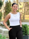 Miik model Meron (5'3", xsmall) smiling wearing Miik's Amina reversible shelf bra tank in white with a black pant