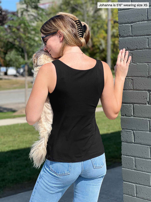 Miik model Johanna (5’6”, xsmall) standing with her back towards the camera showing the back of Miik's Amina reversible shelf bra tank in black