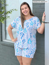 Miik model Christal (five feet three, large) smiling wearing Miik's Amita PJ lounge set in ocean leaf print