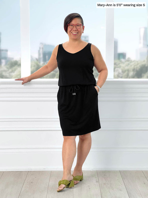 Miik model Mary-An (5'0", small, petite) smiling wearing Miik's Amy drawstring pocket dress in black