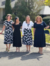 Miik models Yasmine, Christal and Carley along with founder Donna standing next to each other laughing wearing Miik's Anika puff sleeve midi dress in the three colours available: white lily print, black and navy 