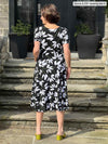 Miik founder Donna (5’6”, small) standing with her back towards the camera showing the back of Miik's Anika puff sleeve midi dress in white lily