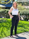 Miik model Andrea (5'10", large, tall) smiling wearing Miik's Asia mid-rise slim pant in black long length with a white tank top and a belt