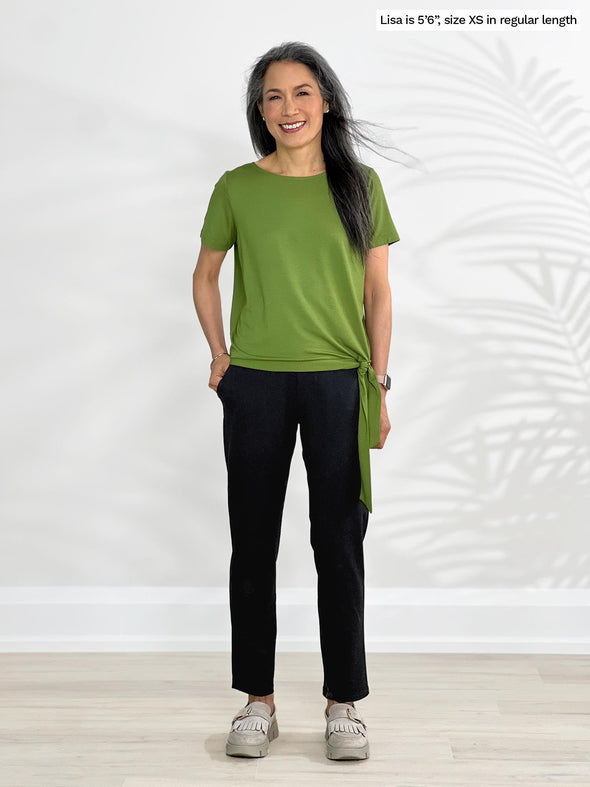 Miik model Lisa (5'6", xsmall) smiling wearing Miik's Asia mid-rise slim pant black in regular length with a green moss top