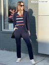 Woman standing in front of a building wearing Miik's Asia mid-rise slim pant in navy with a striped tee and navy cardigan